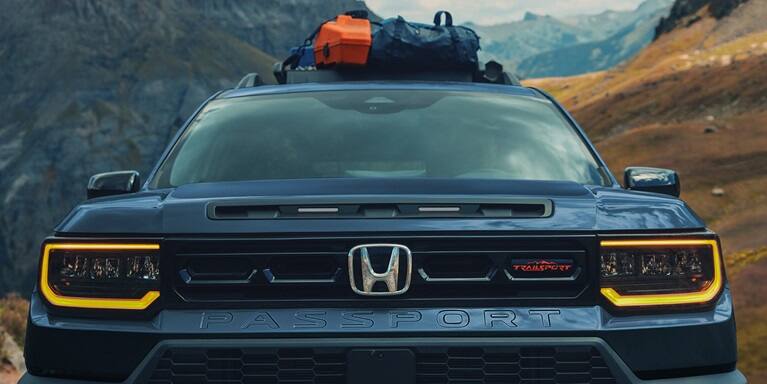 2027 Honda Passport TrailSport Elite in Smoke Blue Pearl front parked in the mountains with gear on the roof (Mid-Size SUV).