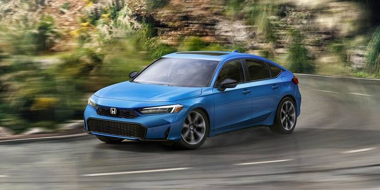 2027 Honda Civic Hatchback Sport Touring Hybrid in Boost Blue Pearl front driving on a winding road (Compact Hatchback).